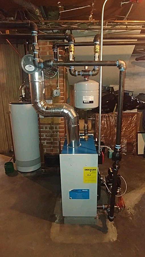 A blue and white boiler is sitting in a basement next to a water heater.