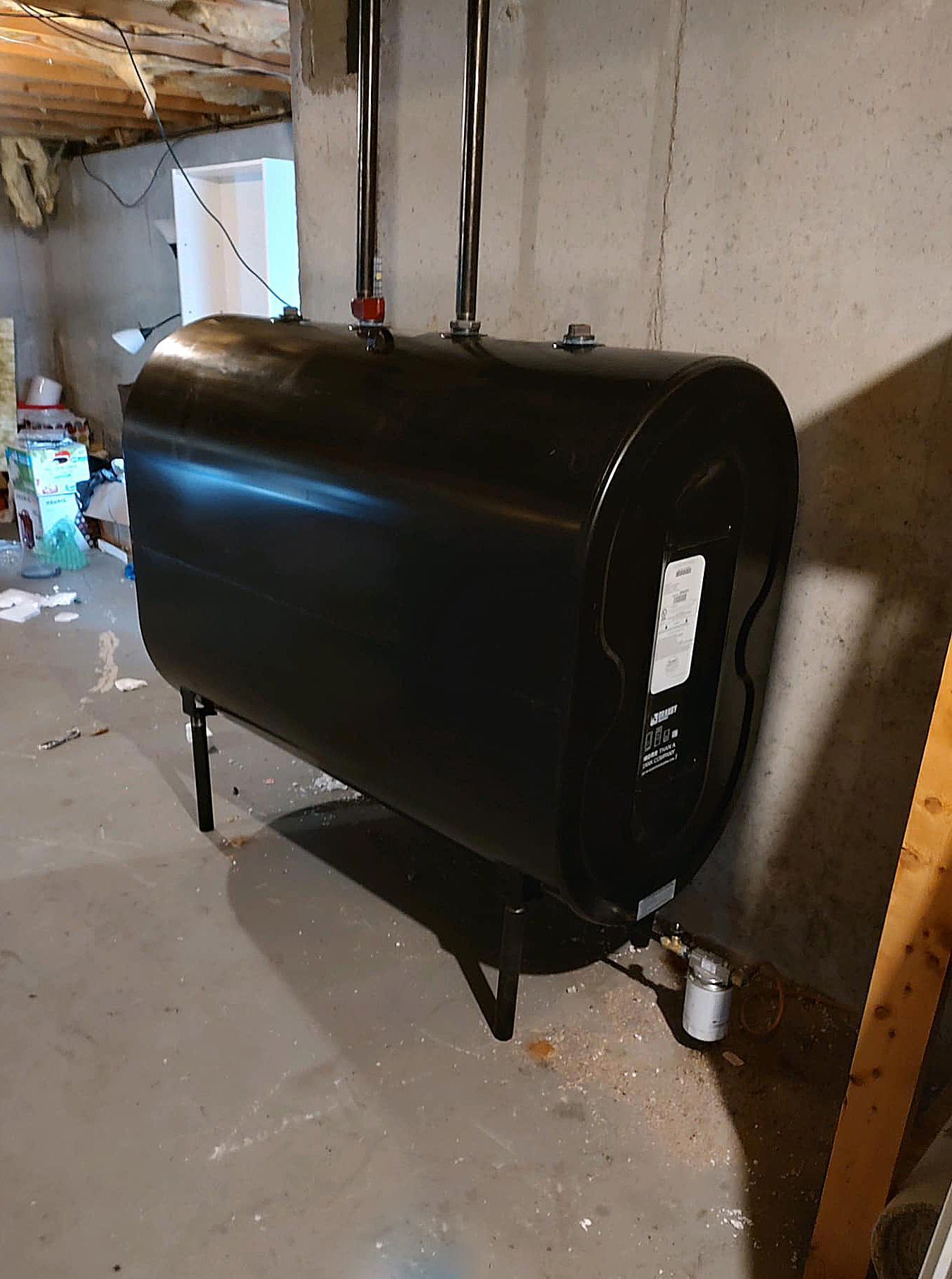 A large black tank is sitting in a basement.
