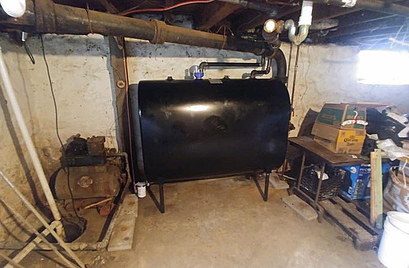 A large black tank is sitting in a basement.
