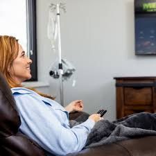 Woman reclining on a couch with a remote, watching TV in a living room