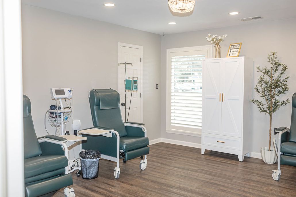 Modern medical treatment room with recliner chair, equipment, and white cabinets