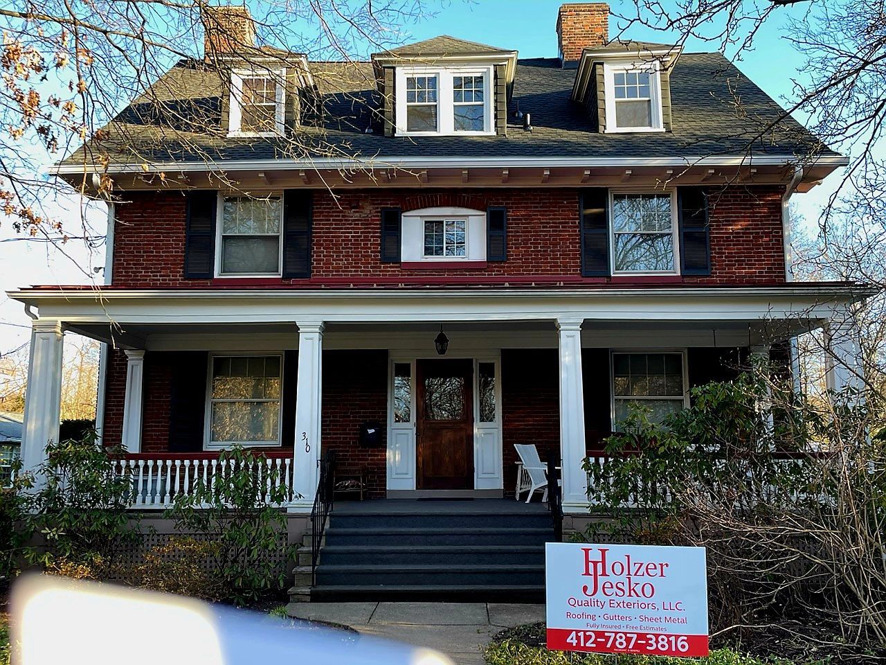 A large brick house with a for sale sign in front of it