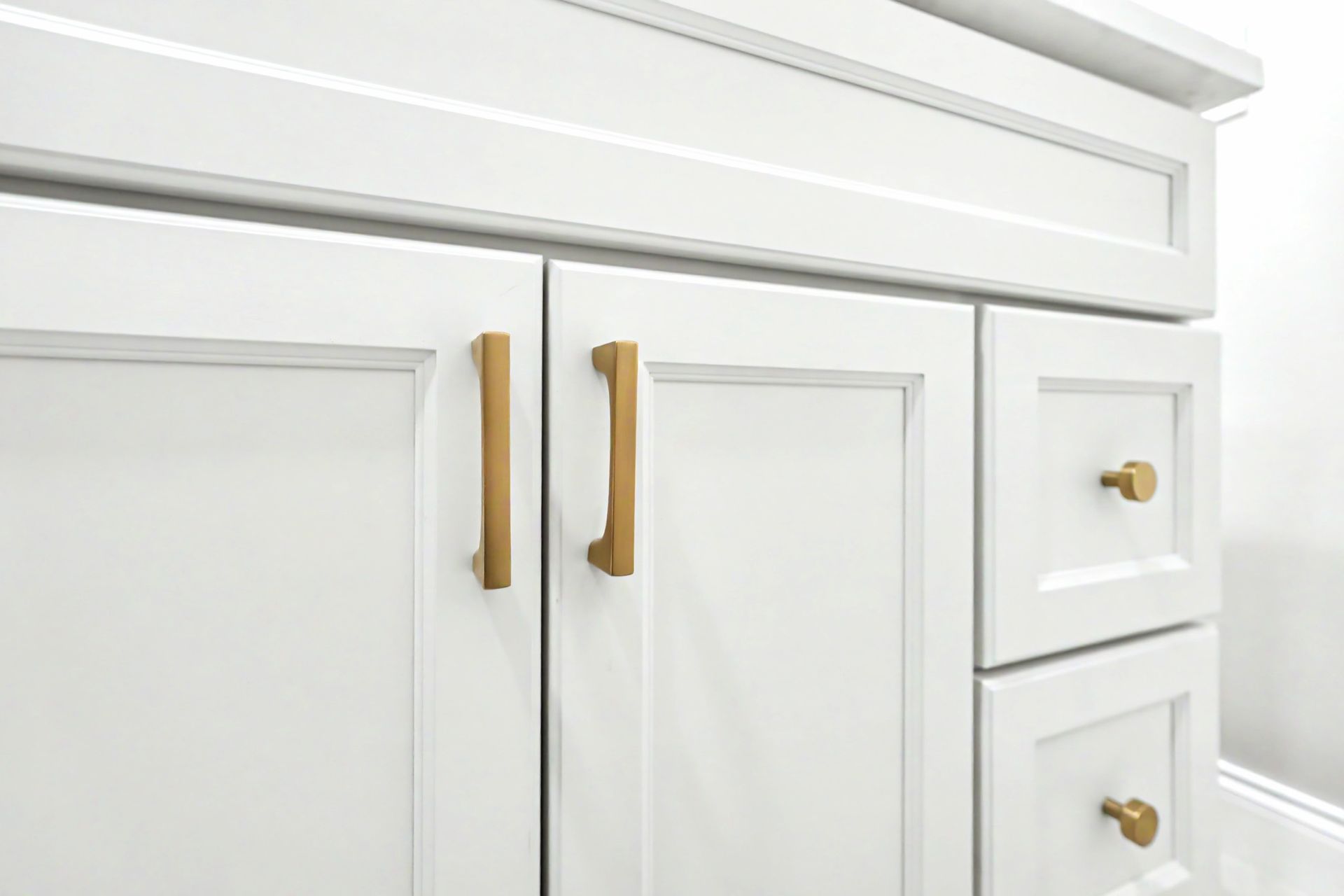 White kitchen cabinets with brass handles and drawers, close-up view