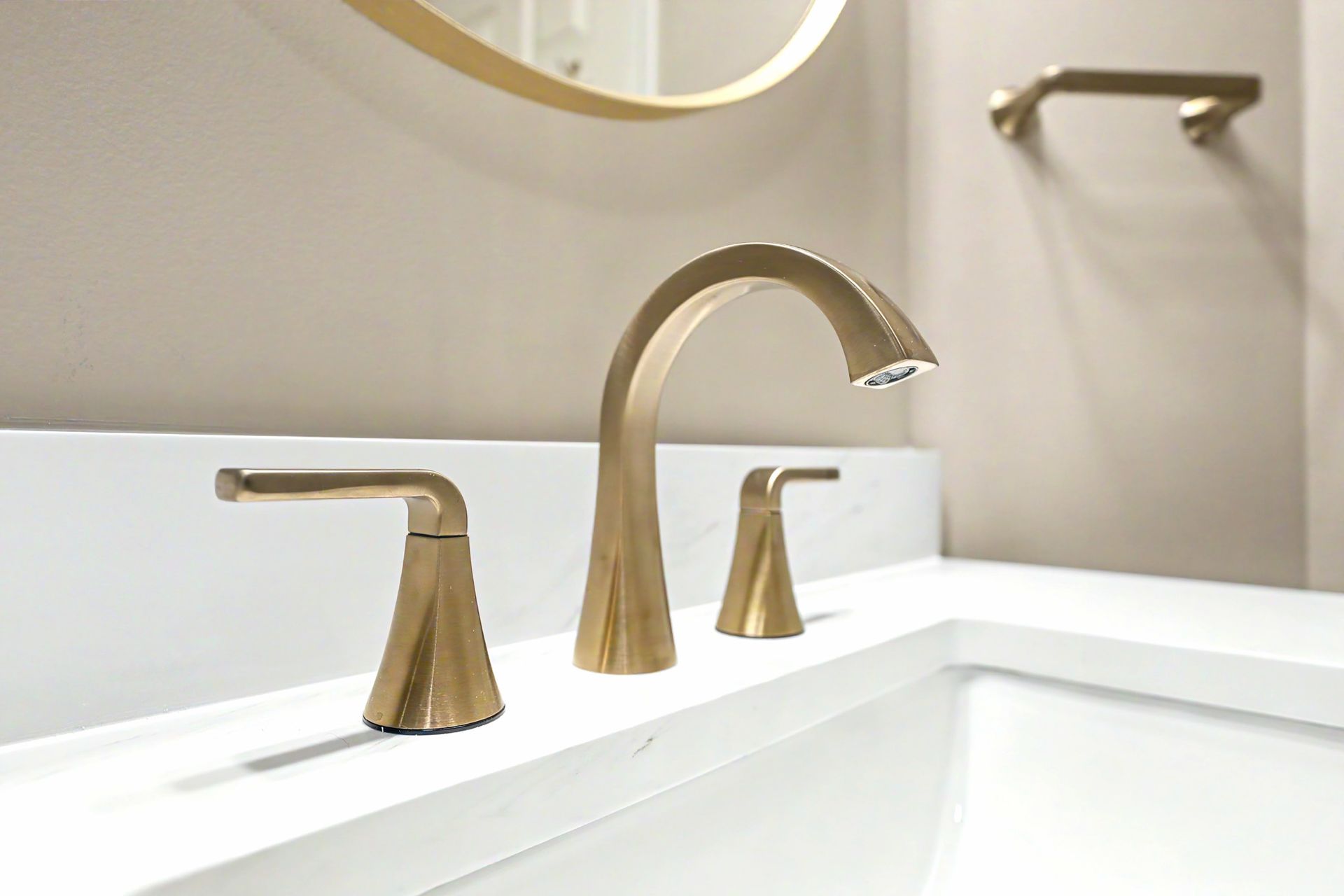 Three gold bathroom faucets over a white sink and countertop