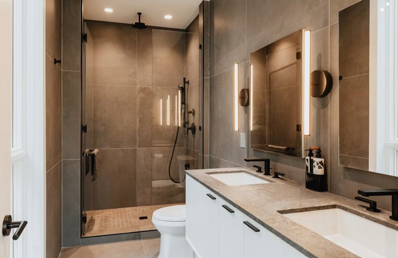 Modern bathroom with double vanity, large mirror, and glass-enclosed shower in neutral tones