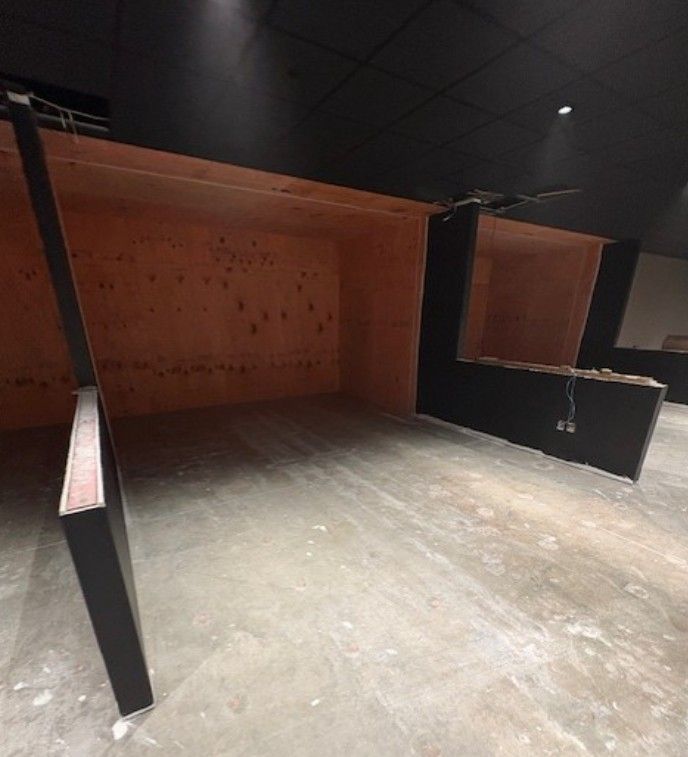 Empty industrial interior with black and orange wooden stalls on a concrete floor