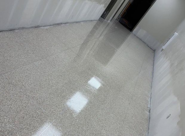 Empty white hallway with a speckled floor and a dark doorway at the end.