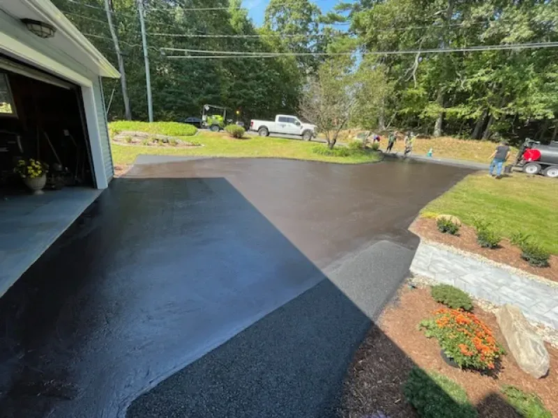 A black driveway is being painted next to a garage