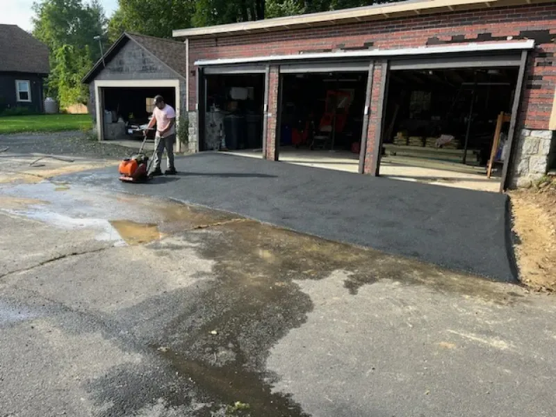 A man is working on a driveway in front of a garage
