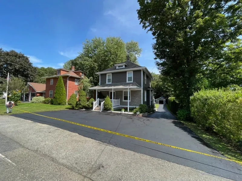 A house is sitting on the side of the road next to another house