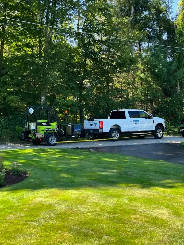 A white truck is parked on the side of the road with a trailer attached to it