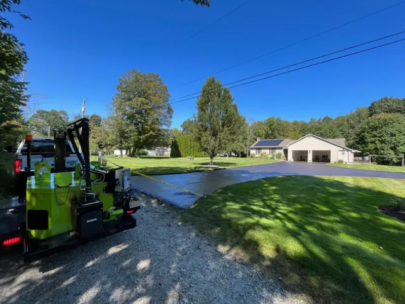 A green truck is parked in a driveway next to a house