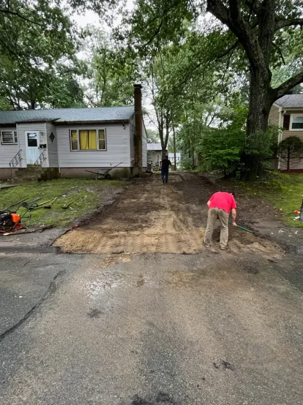 A man is working on a driveway in front of a house