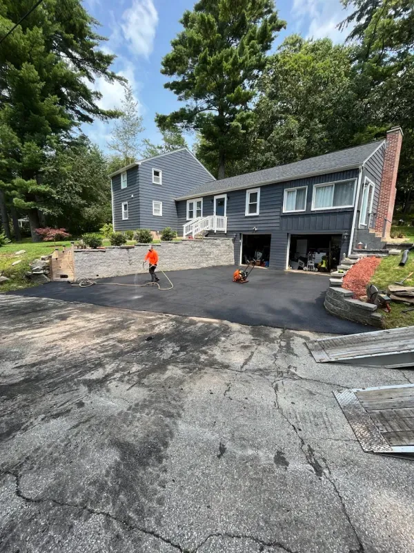 A man is standing in a driveway in front of a house