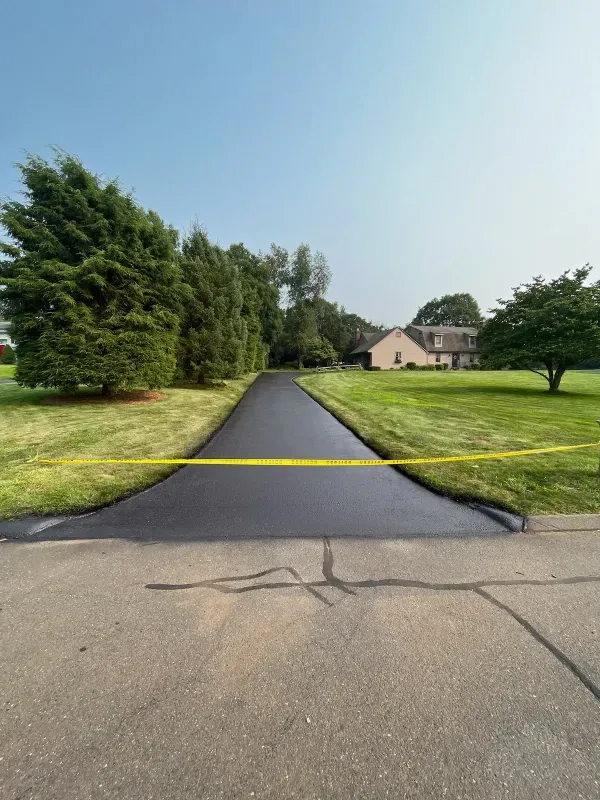 A driveway with a yellow tape along the side of it and a house in the background