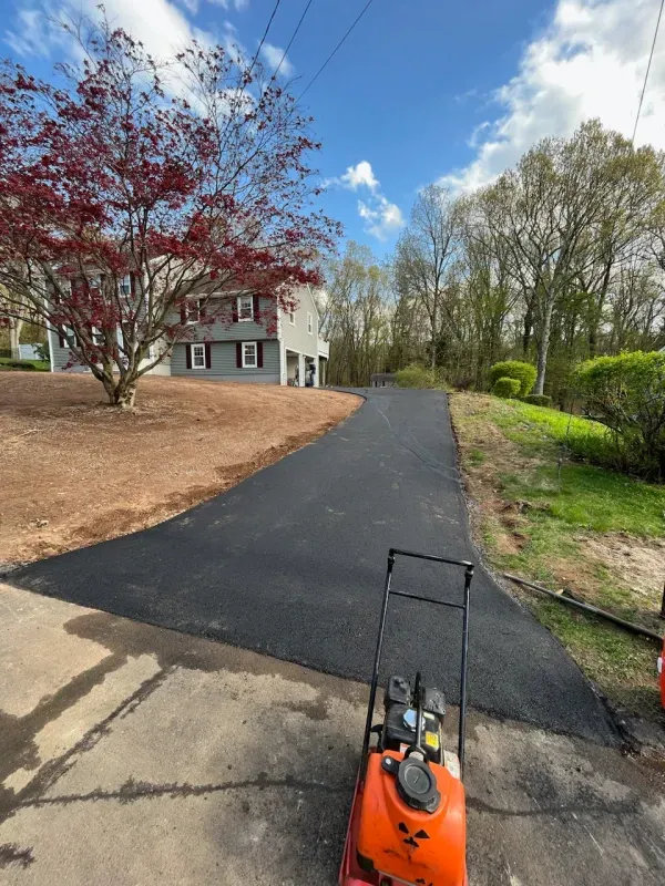 A lawn mower is parked on the side of a road next to a house
