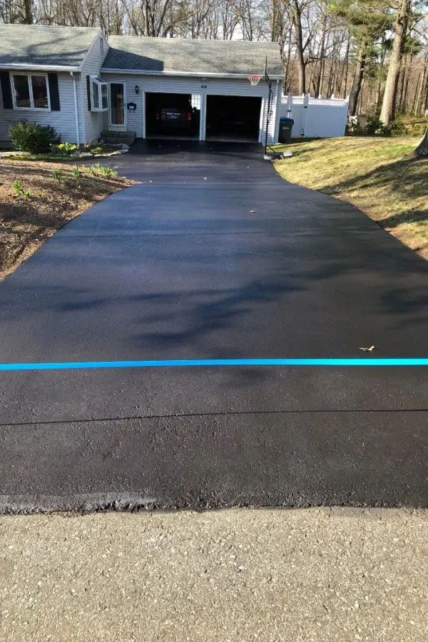 A black driveway leading to a house with a blue line on it