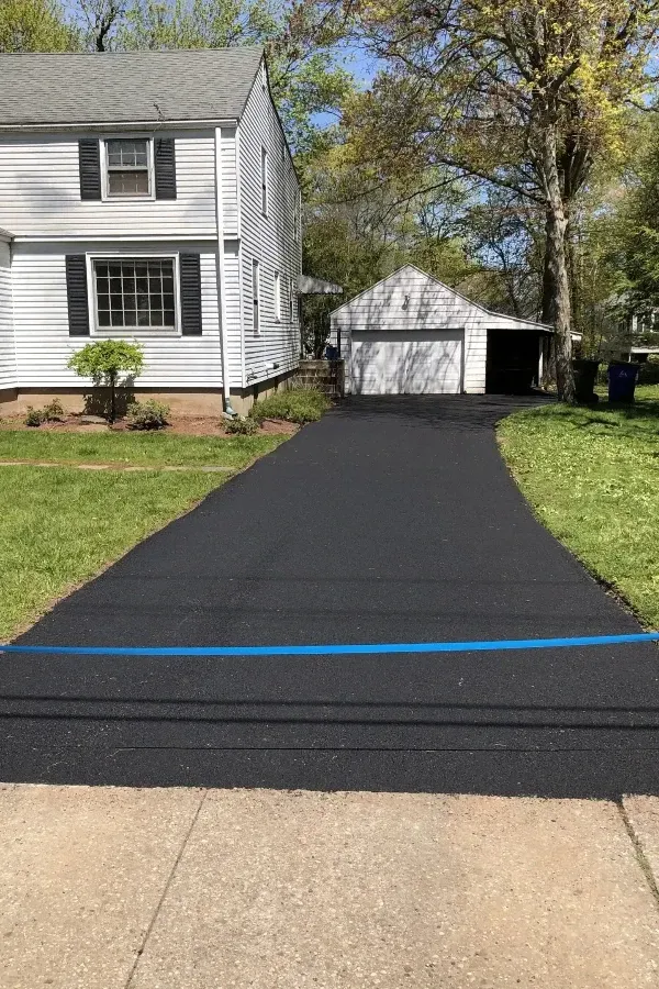A black driveway leading to a white house with a garage
