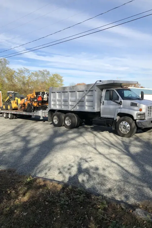 A dump truck with a trailer attached to it is parked on the side of the road