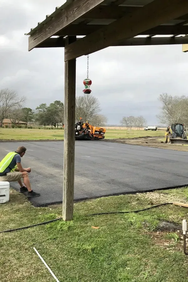 A man is sitting under a covered area while a truck is driving down the road