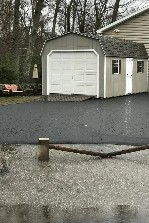 A garage with a white door is in a driveway next to a house