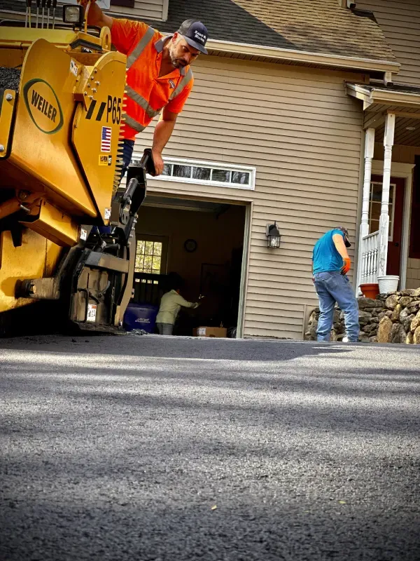 A man is working on a road in front of a house