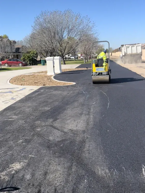 A man is driving a yellow roller down a road
