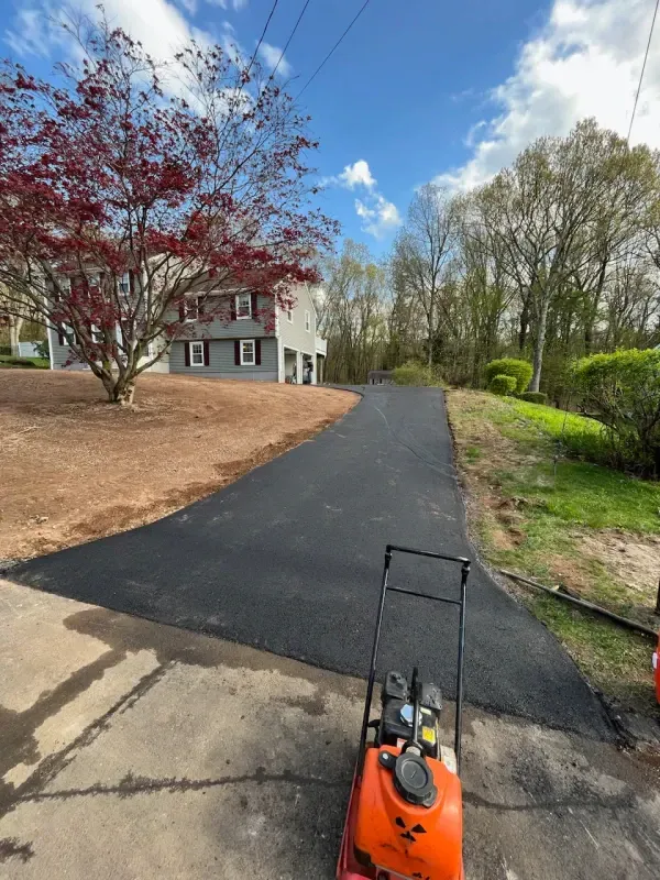 A lawn mower is parked on the side of a road next to a house