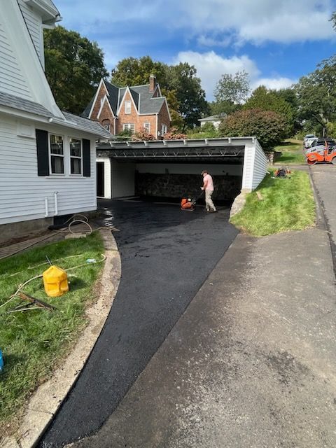 A man is working on a driveway next to a house