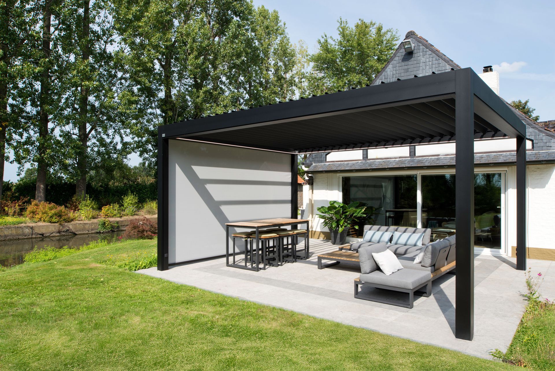 A patio with a pergola and a table and chairs in front of a house.