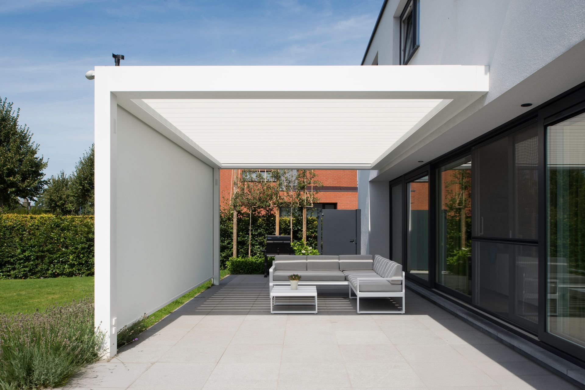 A patio with a pergola and sliding glass doors.