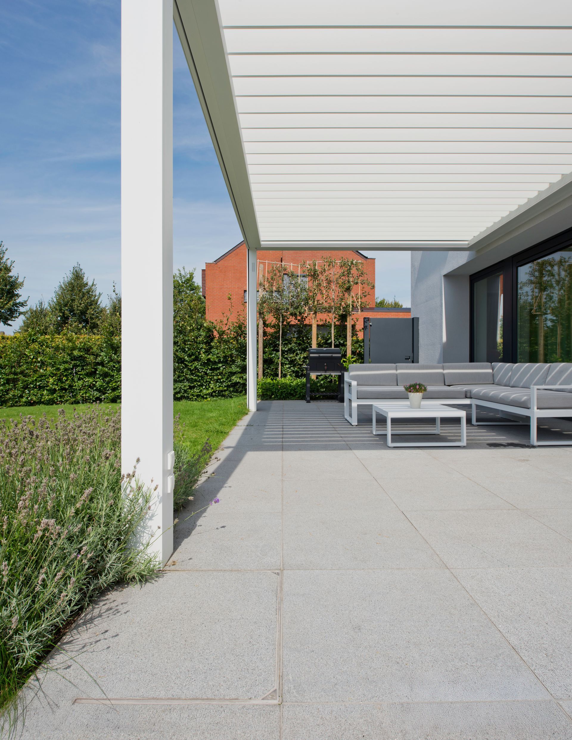 A patio with a couch and a table under a pergola.