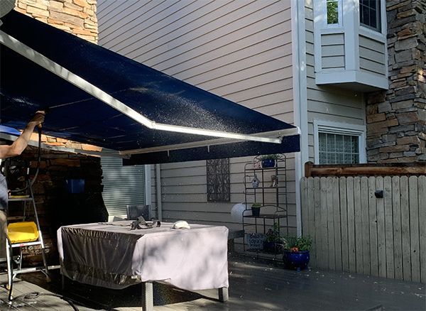 a man is holding a blue awning over a table in front of a house