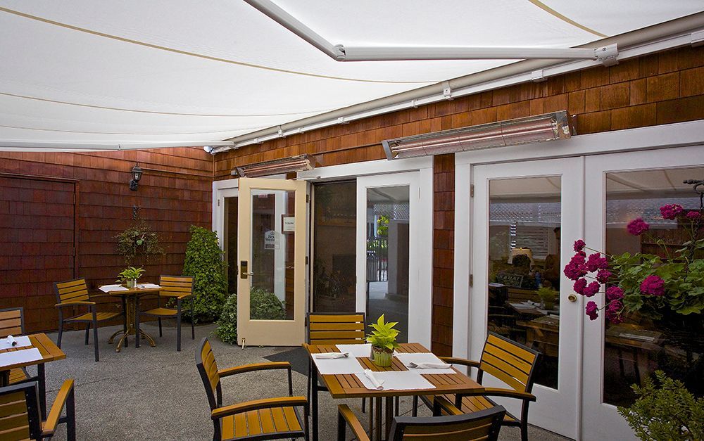 a patio with tables and chairs under an awning