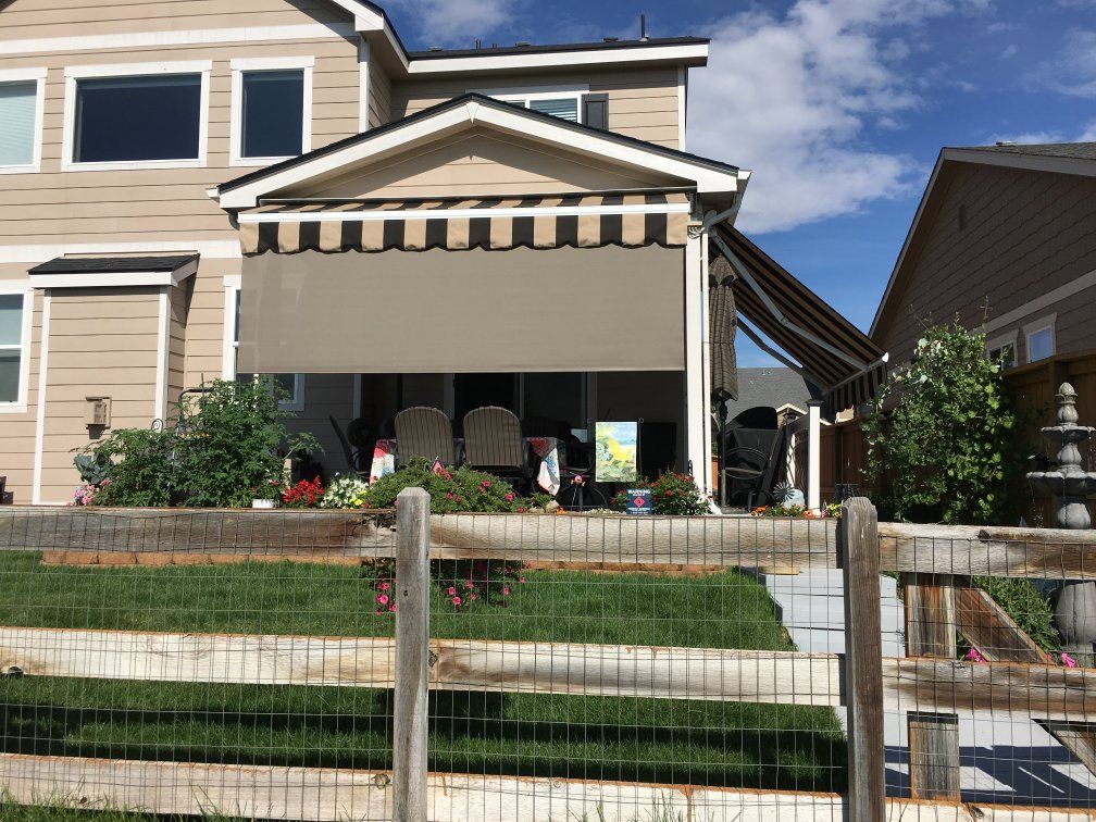 a house with a black and white awning on the porch