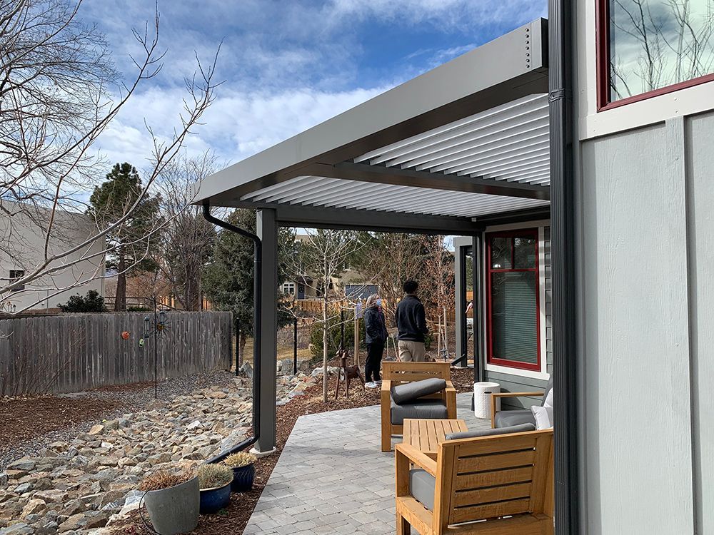 a couple of people standing on a patio under a pergola