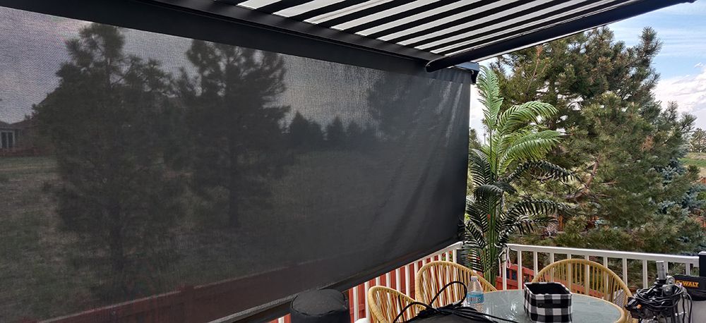 a black awning is covering a patio with trees in the background