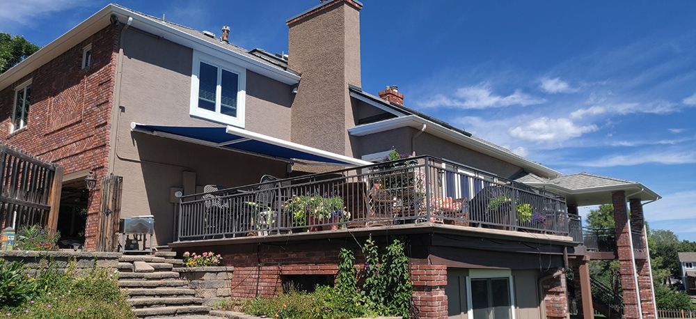 a large brick house with a balcony and awning on a sunny day