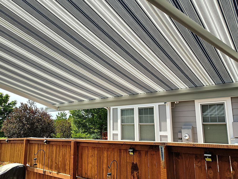 a striped awning is covering a wooden fence in front of a house