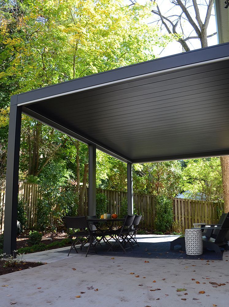 a black pergola with a table and chairs underneath it