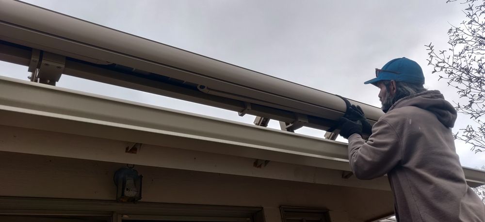 a man is fixing a gutter on the roof of a house