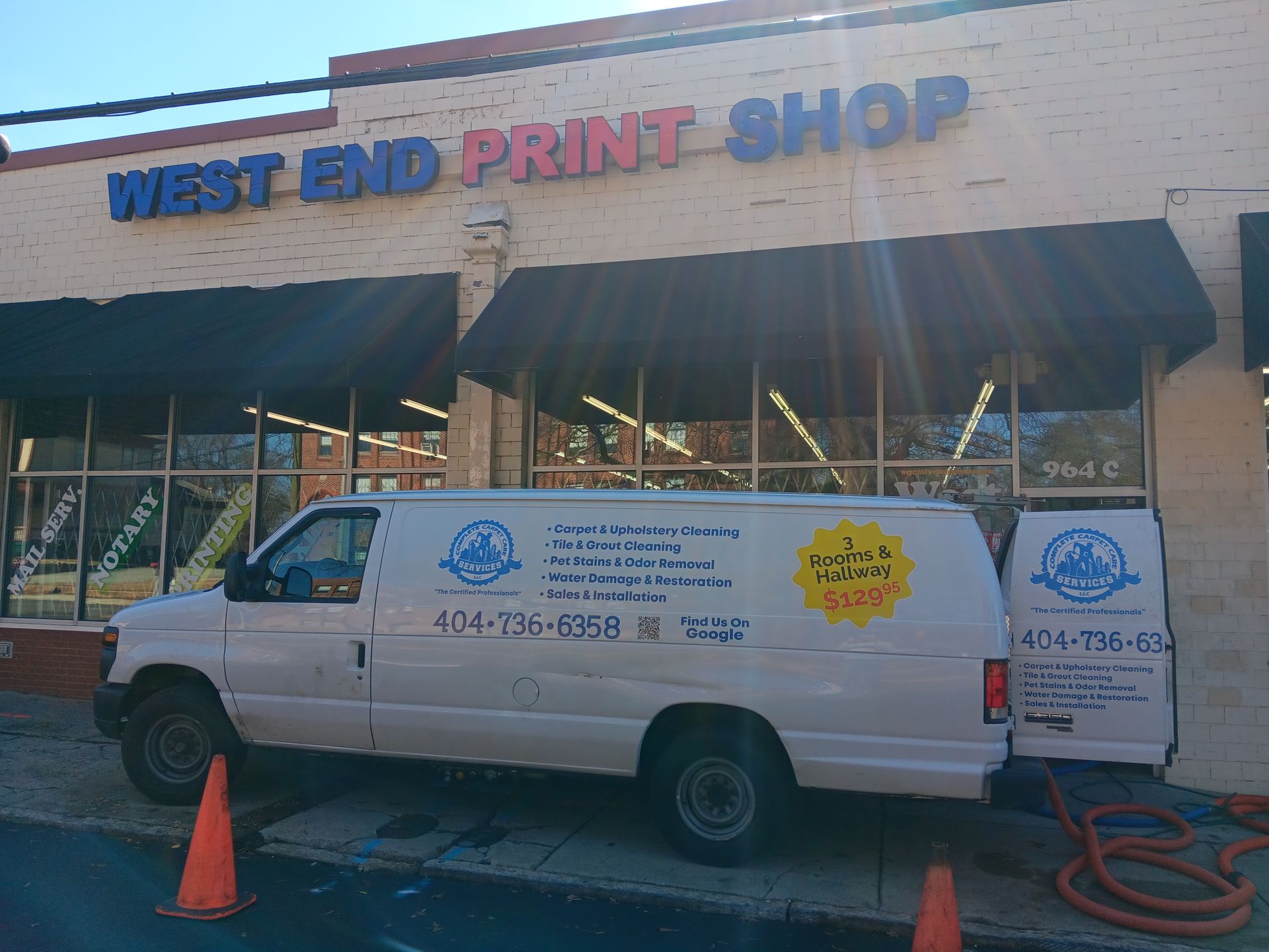 White van with logos parked in front of West End Print Shop with black awning.