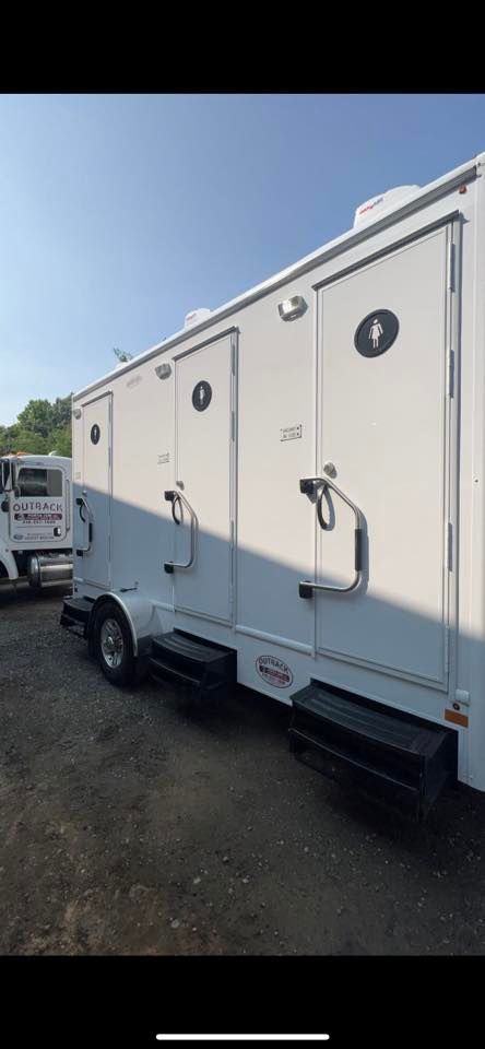 a white trailer with two toilets on it is parked in a parking lot 