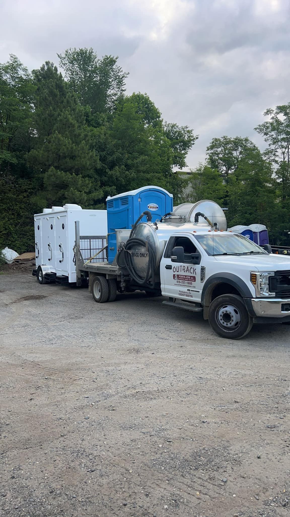 a white truck with a trailer attached to it is parked in a gravel lot