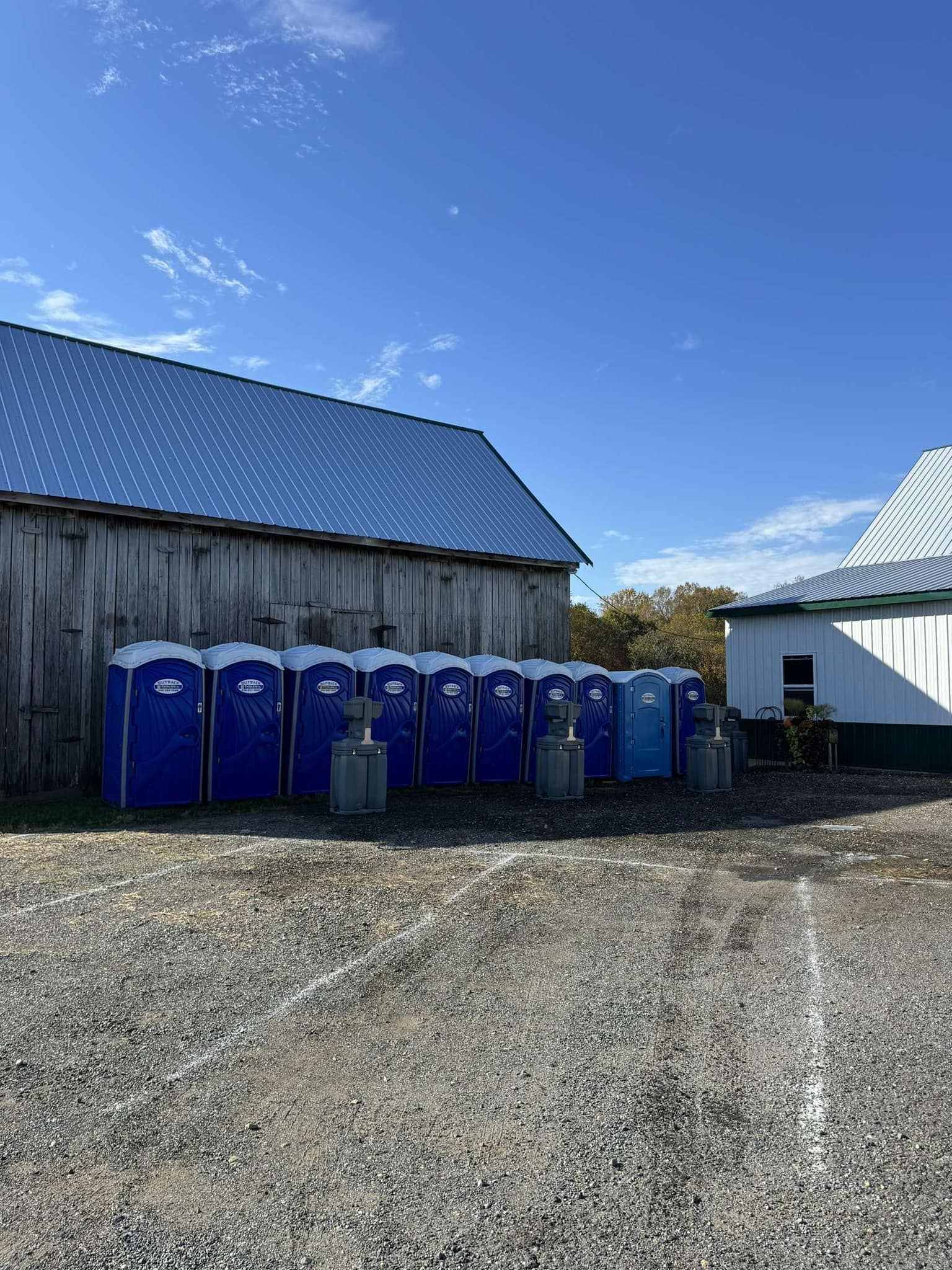 a row of portable toilets are lined up in front of a barn