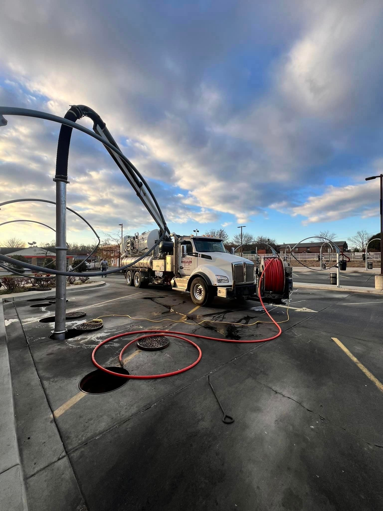 a white truck with a crane attached to it is parked on the side of the road