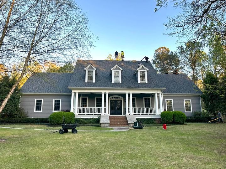 Two men are working on the roof of a large house.