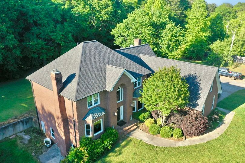 An aerial view of a large brick house surrounded by trees.