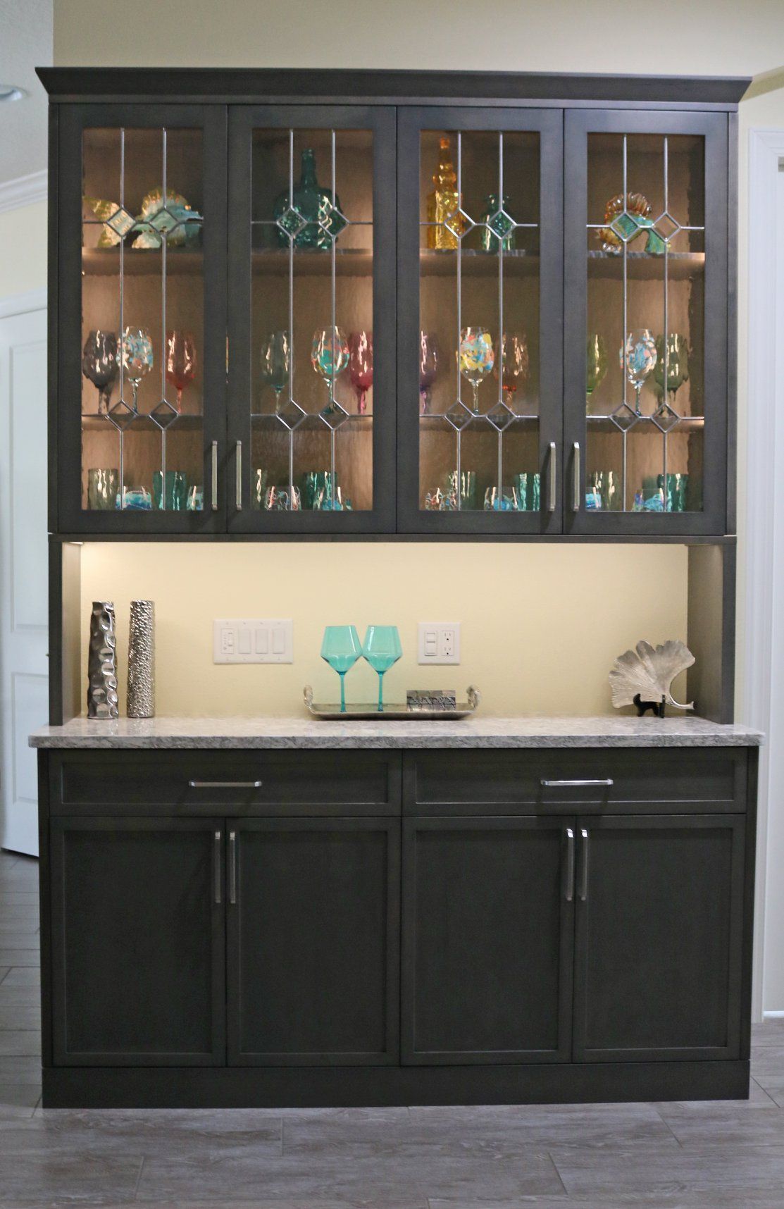 A cabinet with glass doors filled with wine glasses