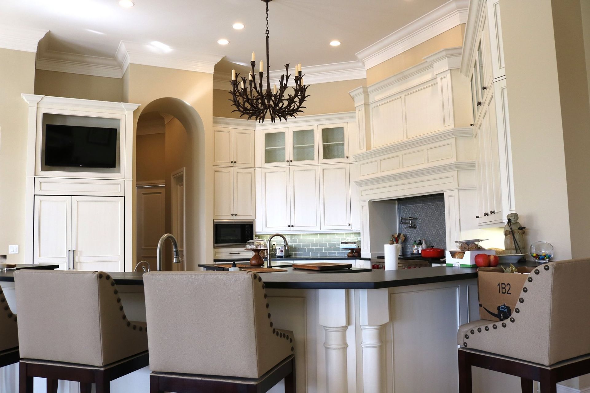 A kitchen with white cabinets and black counter tops and a chandelier hanging from the ceiling.